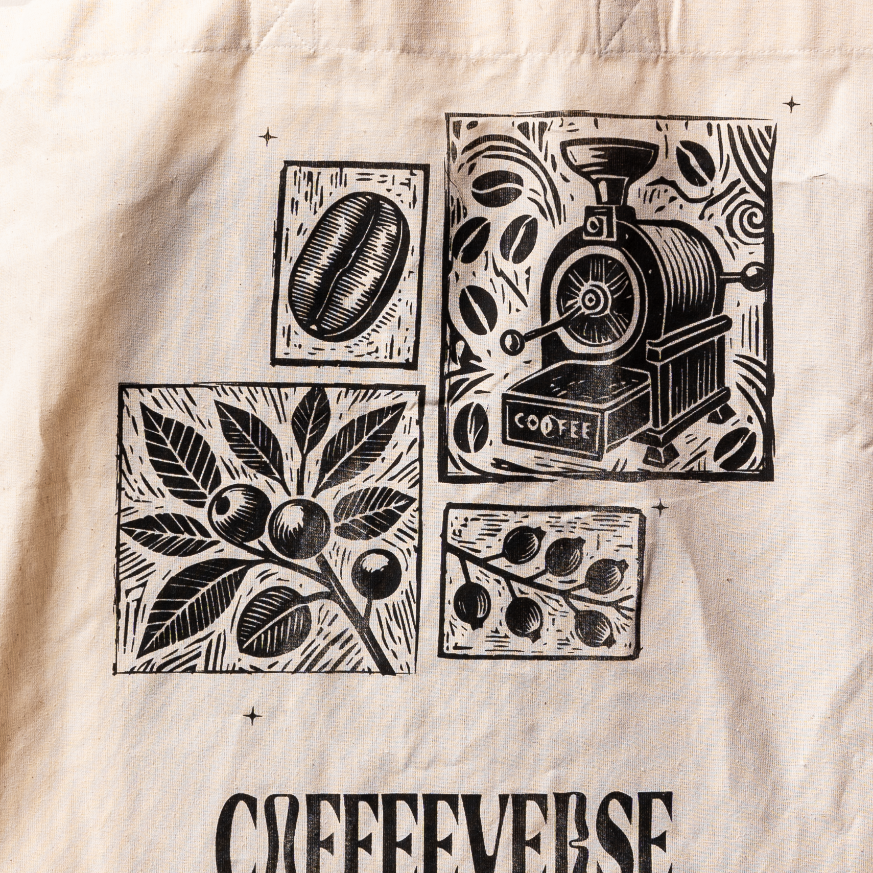A beige cotton tote bag with black coffee-related illustrations, including a coffee bean, coffee machine, and leaves. The brand name 'COFFEEVERSE' is printed at the bottom.