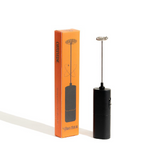 Black milk frother with orange packaging on a white background